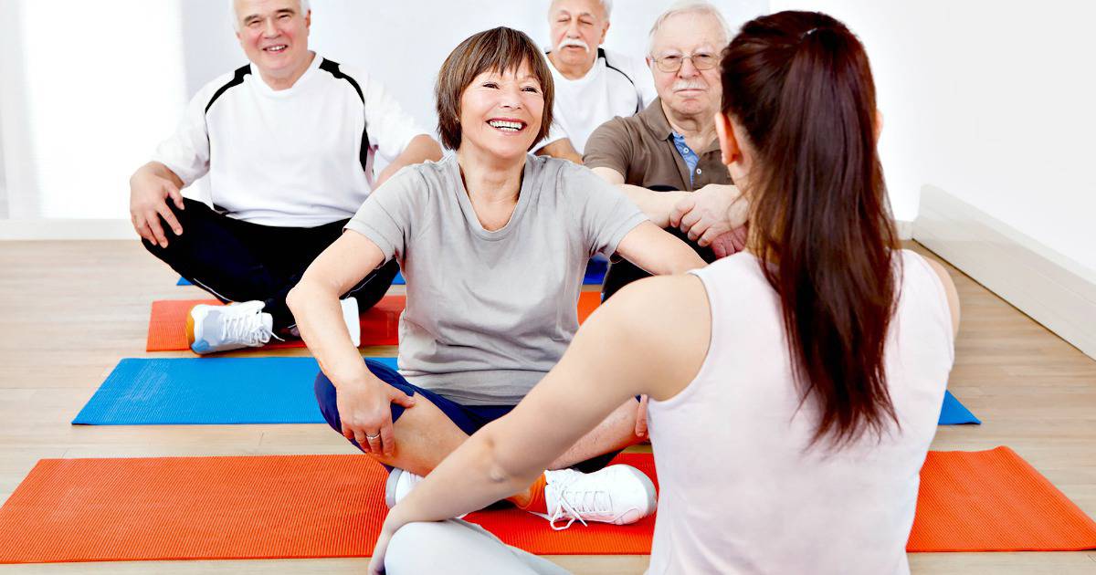Group of older adults sitting on fitness mats